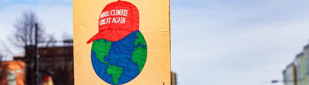 Pancarte en carton avec une image de la Terre coiffée de la casquette de Trump sur laquelle est inscrit « Make climate great again », lors d’une manifestation pour l’environnement. 